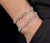 Two XO moissanite tennis bracelets stacked on wrist white gold iced out pave bracelet set