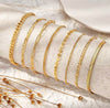 21 gold anklets laid flat showing all styles — ball bead, satellite, rope, Cuban, herringbone, tennis, coin disc, and more by Twelfth XII