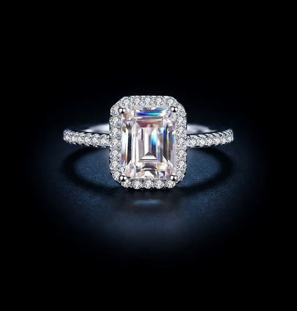 2ct emerald cut moissanite halo engagement ring in S925 sterling silver four-claw pavé setting on dark background — Twelfth XII