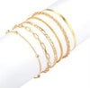 6 piece 14K gold stacked anklet set displayed on ankle — snake, figaro, paperclip, box, rope, and satellite chain styles