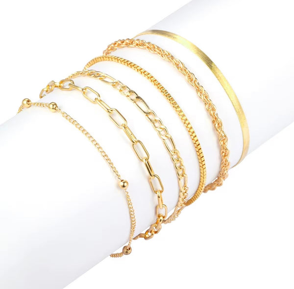6 piece 14K gold stacked anklet set displayed on ankle — snake, figaro, paperclip, box, rope, and satellite chain styles