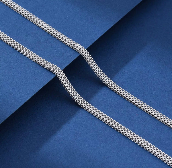 Full-length 4mm double Franco chain necklace in 925 sterling silver draped on royal blue surface