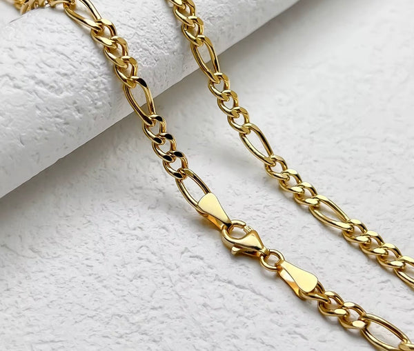 2.5mm 18K solid gold Figaro chain necklace with lobster clasp detail shown on white marble surface