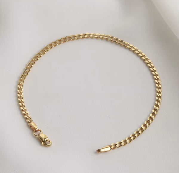 A gold-toned curb chain bracelet with a lobster clasp and tip, displayed on a light gray background.