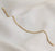 A gold chain bracelet with a lobster clasp, displayed on a draped white fabric background.