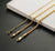 Three solid 18k gold foxtail chain necklaces in 1.3mm, 2mm, and 2.7mm draped over a marble block